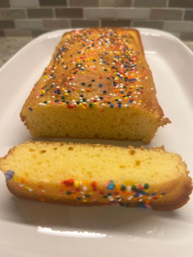Loaf of cake with colorful sprinkles, sliced to reveal a soft, moist interior. This small cake made with 1 cup of cake mix is a simple, fun treat perfect for celebrations or a quick dessert.