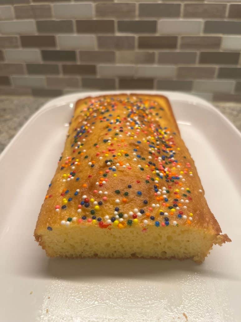 A close-up view of a loaf cake topped with colorful sprinkles, showcasing a simple and fun dessert made with 1 cup of cake mix.