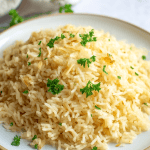 Fluffy and golden garlic butter rice garnished with fresh parsley, perfect as a flavorful side dish.