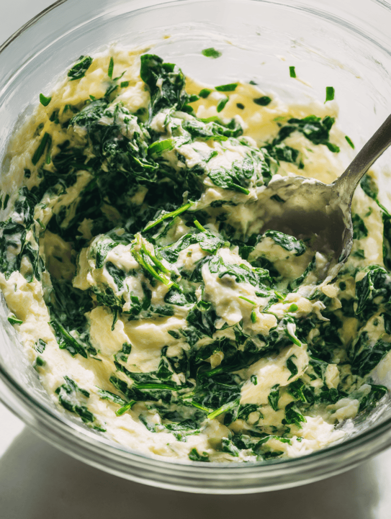 Spinach and ricotta cheese filling being mixed in a glass bowl—an essential step in preparing the stuffed shells.