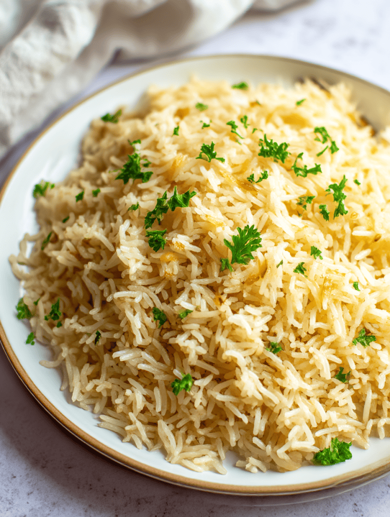 A close-up of fluffy garlic butter rice topped with fresh parsley, served on a white plate.