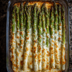 Cheesy baked asparagus in a glass baking dish, fresh from the oven, with golden melted mozzarella.