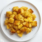 Serving of golden pineapple stuffing on a white plate, showcasing the fluffy texture and sweet baked flavor.