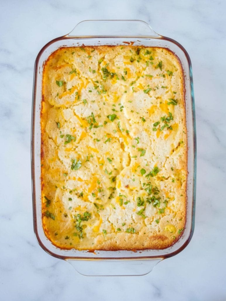Freshly baked TikTok chicken cobbler in a glass dish with a golden biscuit topping and parsley garnish, just out of the oven.