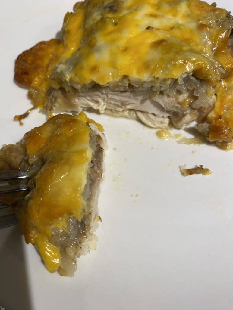 Close-up of a cheesy baked chicken thigh with a slice cut to reveal the juicy inside, tender and melty final result.