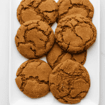 Soft and chewy gingersnap cookies with crackled tops arranged on a white rectangular plate – the perfect homemade holiday treat.