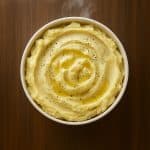 A bowl of creamy roasted garlic mashed potatoes, swirled with butter and black pepperโperfect for a cozy homemade side dish.