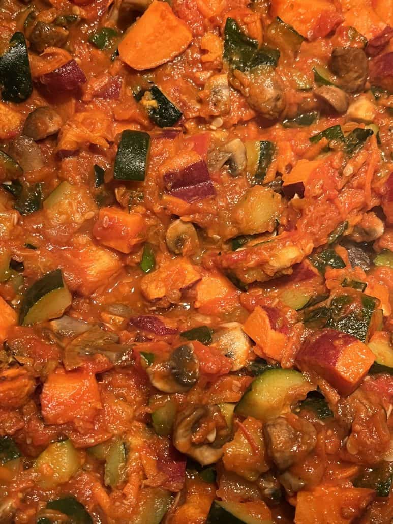 Zoomed-in view of Sweet Potato Mushroom and Zucchini Skillet featuring vibrant, sautéed vegetables in a thick tomato sauce.