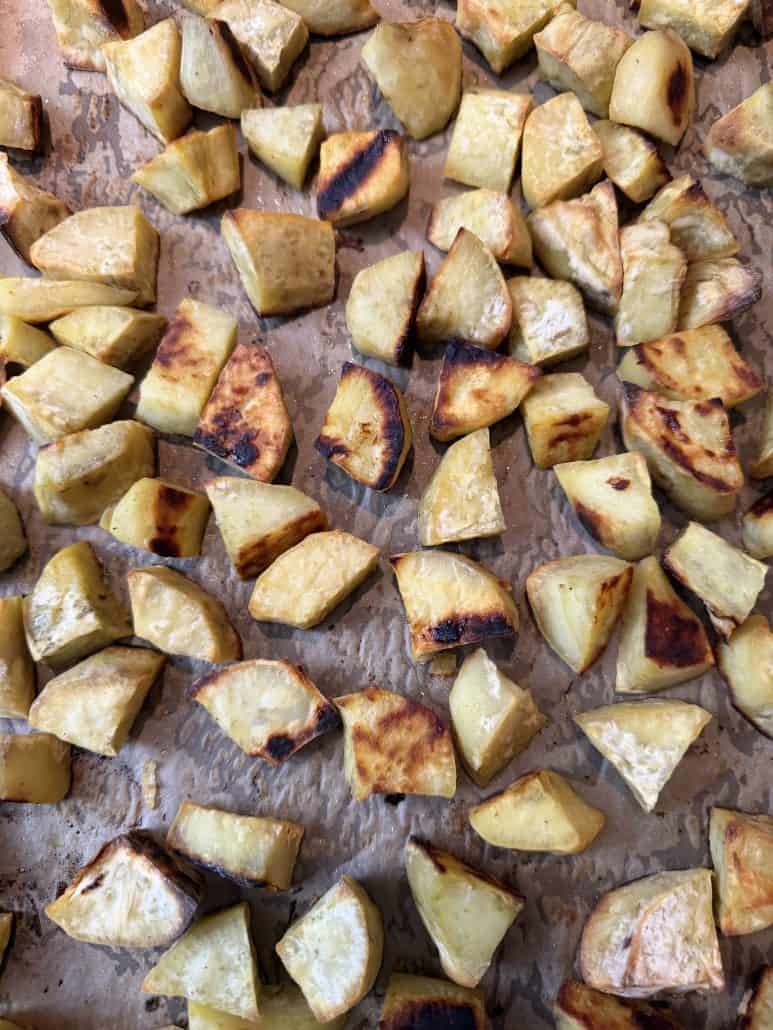 Top view of evenly roasted white sweet potato chunks on parchment paper, showcasing their golden brown color and crisp texture.