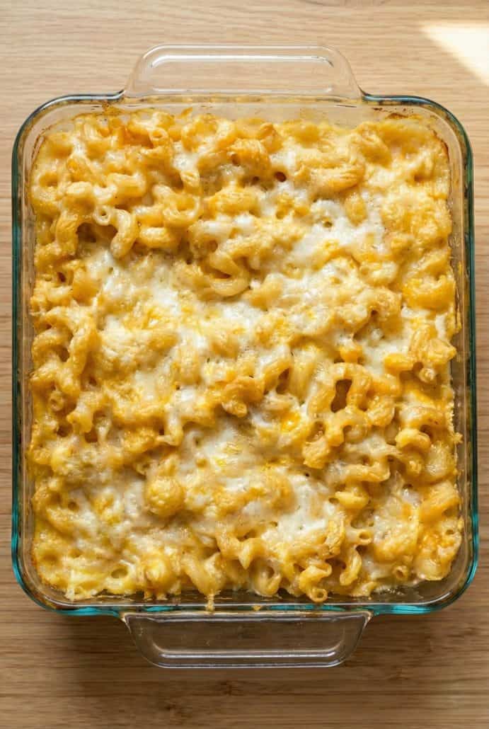 Freshly baked macaroni and cheese in an 8x8 glass dish with a melted golden cheese topping, just out of the oven and ready to serve.