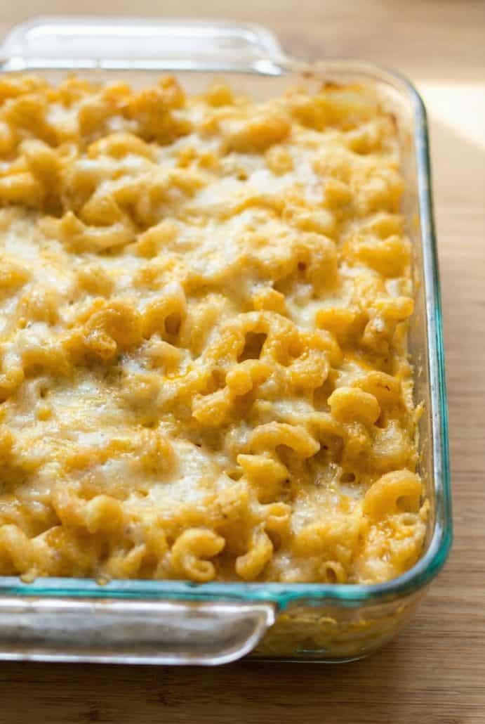 Close-up of creamy baked macaroni and cheese in a glass dish, highlighting the melted cheddar topping and golden edges from the oven.