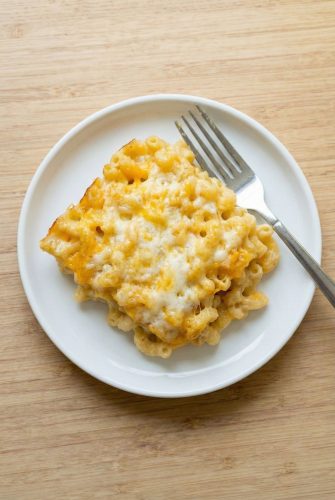 Oven-Baked Macaroni and Cheese Recipe - Simple & Delicious A serving of baked macaroni and cheese on a white plate with a fork, showing the golden, cheesy top from the oven.