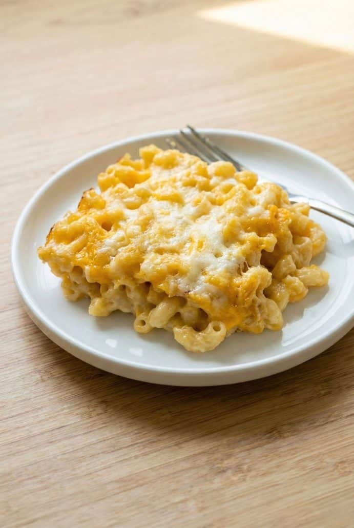 Baked macaroni and cheese served on a white plate with a fork, showing the creamy texture and cheesy top from the finished recipe.