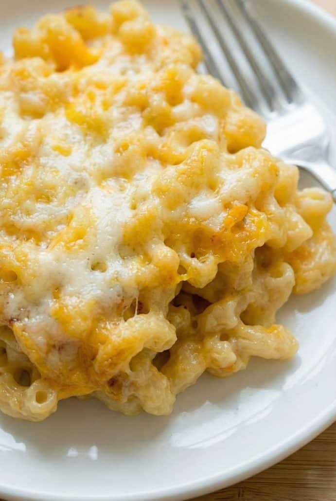 Close-up of a cheesy serving of baked macaroni and cheese on a plate, showing the gooey melted cheese and creamy pasta.