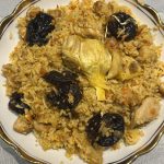 Plate of One-Pot Chicken and Rice Pilaf with prunes, garlic bulb, and tender chicken.