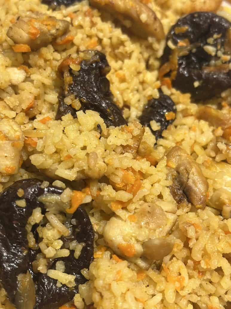 Zoomed-in view of One-Pot Chicken and Rice Pilaf, highlighting tender chicken pieces, prunes, and fluffy seasoned rice.