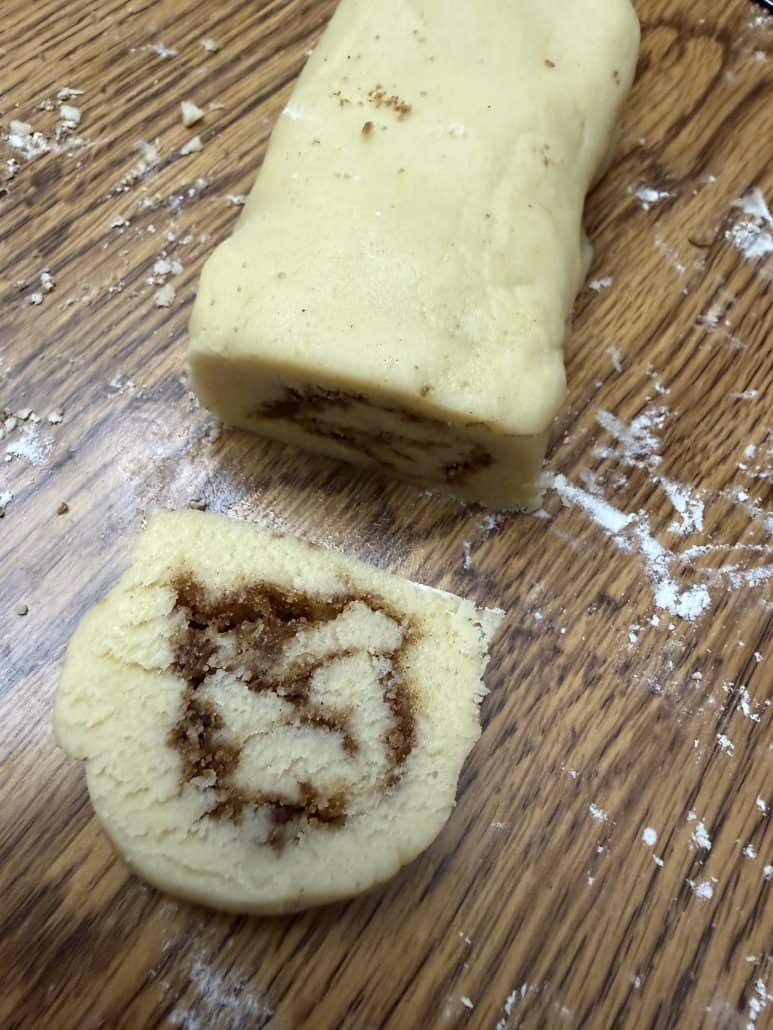 Rolled cookie dough log sliced into a cinnamon swirl round for No Chill Cinnamon Roll Cookies.