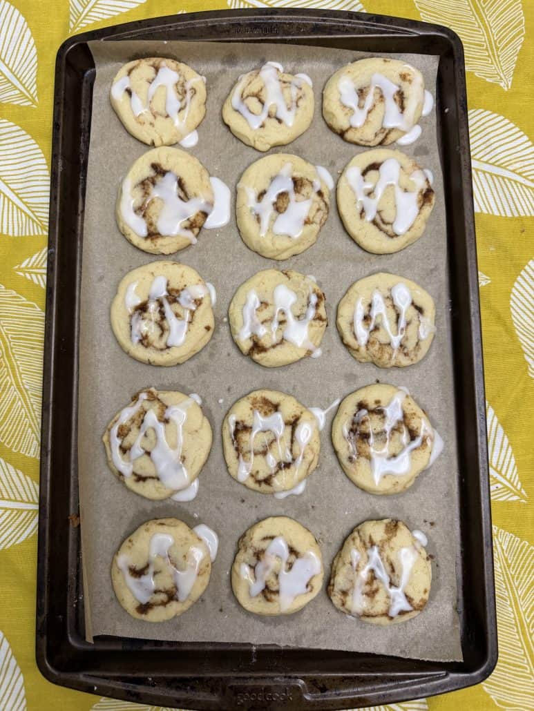 Baked No Chill Cinnamon Roll Cookies on a tray, drizzled with vanilla glaze and ready to serve.