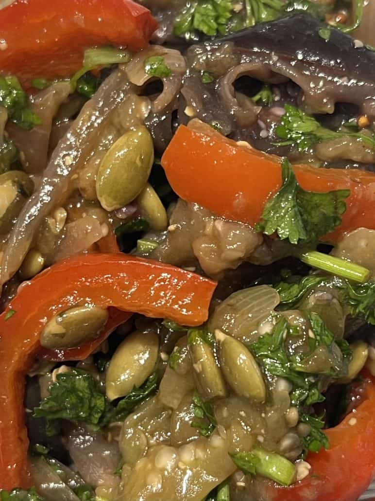 Close-up of marinated eggplant and bell pepper salad with parsley and pumpkin seeds, showing the vibrant texture and freshness of the featured recipe.