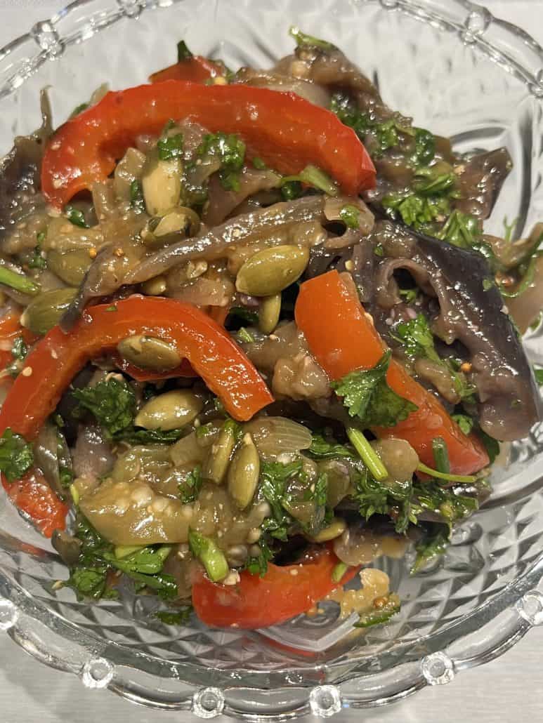 Close-up of marinated eggplant and bell pepper salad in a glass bowl, featuring colorful vegetables and herbs from the featured recipe.