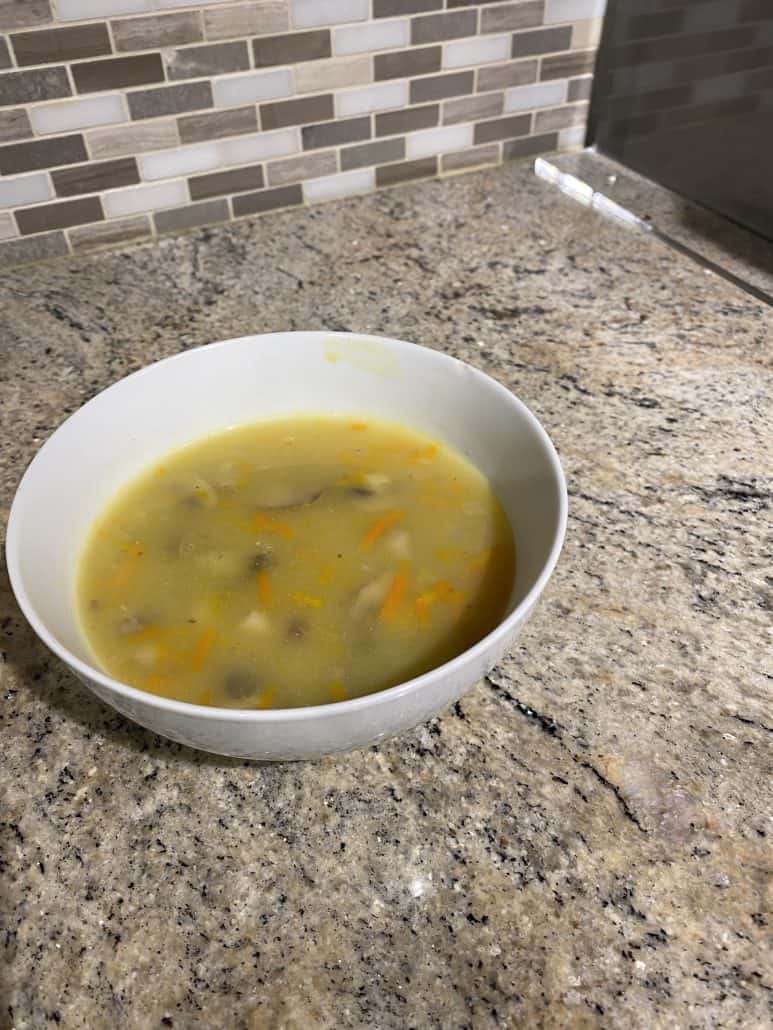 Bowl of homemade chunky mushroom soup on a kitchen counter, ready to serve.