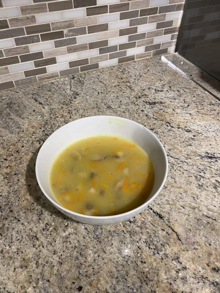 Bowl of chunky mushroom soup on a kitchen counter, showing the hearty texture and vegetables featured in the recipe.