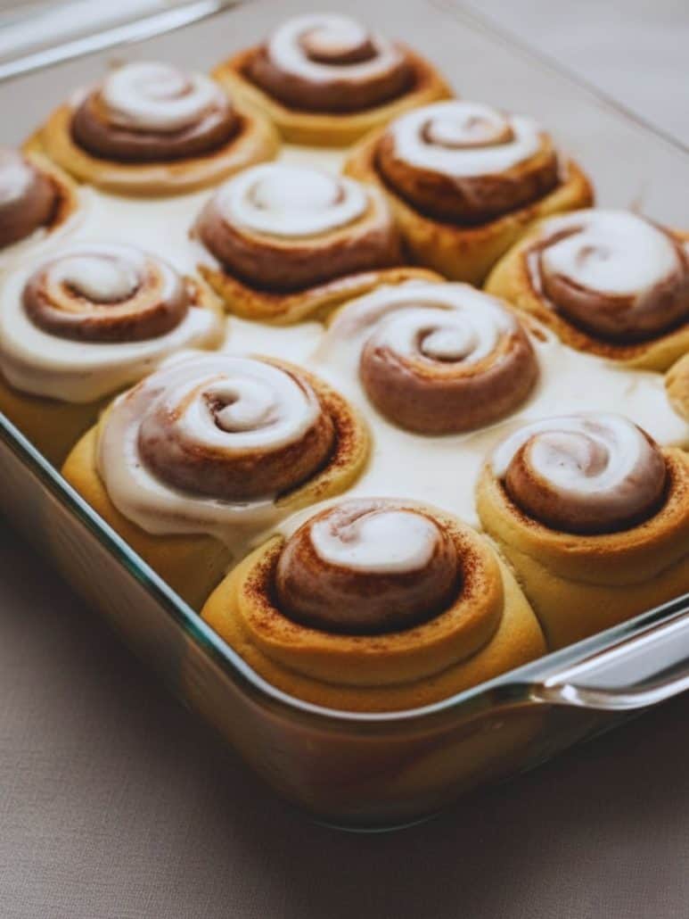 Close-up of soft and fluffy overnight cinnamon rolls in a glass baking dish, topped with melty vanilla glaze — fresh out of the oven and ready to enjoy.