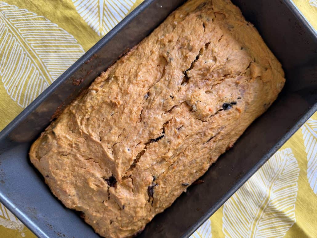 Close-up of freshly baked sweet potato bread in a loaf pan, highlighting its golden crust and soft texture.