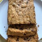 Sliced loaf of sweet potato bread with chocolate chips on a white plate, moist and golden.
