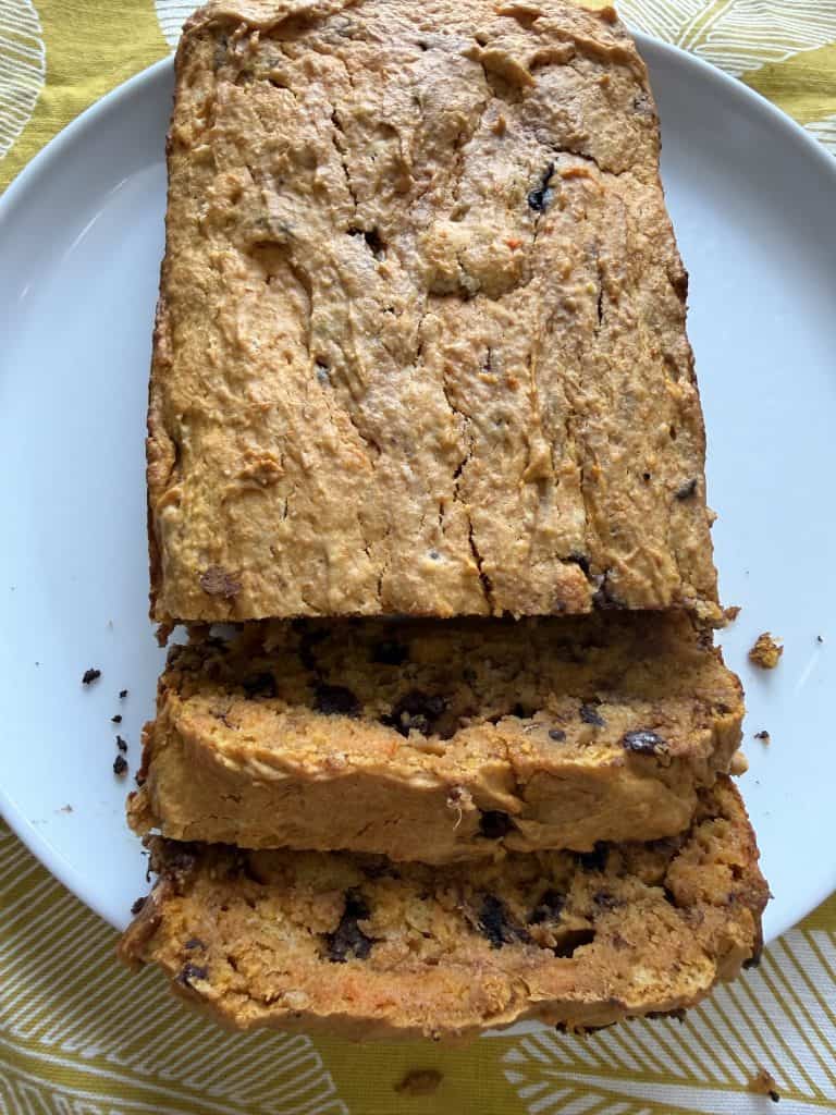 Sliced loaf of sweet potato bread with chocolate chips on a white plate, moist and golden.