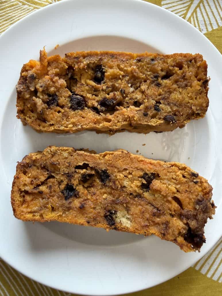 Two slices of sweet potato bread with chocolate chips on a white plate, showing the moist, rich interior from the homemade recipe.