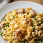 Close-up of cheesy tuna casserole with macaroni, peas, and golden melted cheese, showing the creamy texture and baked finish