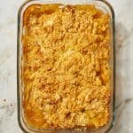 Freshly baked 3 Ingredient Cake Mix Peach Cobbler in a glass baking dish, featuring a golden, buttery topping over sweet canned peaches.