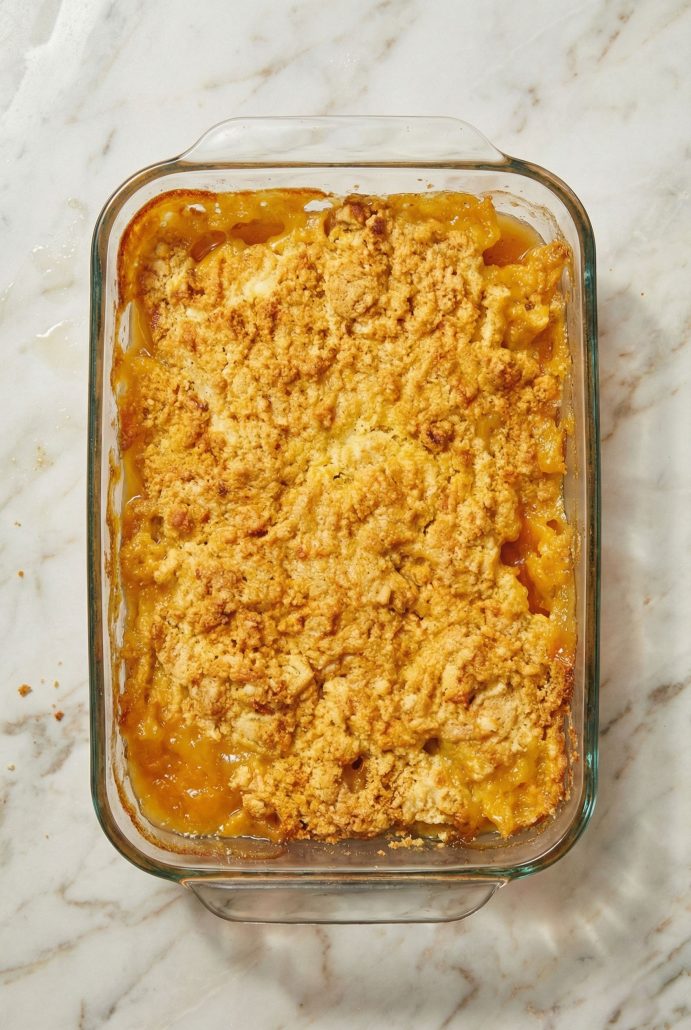 Freshly baked 3 Ingredient Cake Mix Peach Cobbler in a glass baking dish, featuring a golden, buttery topping over sweet canned peaches.