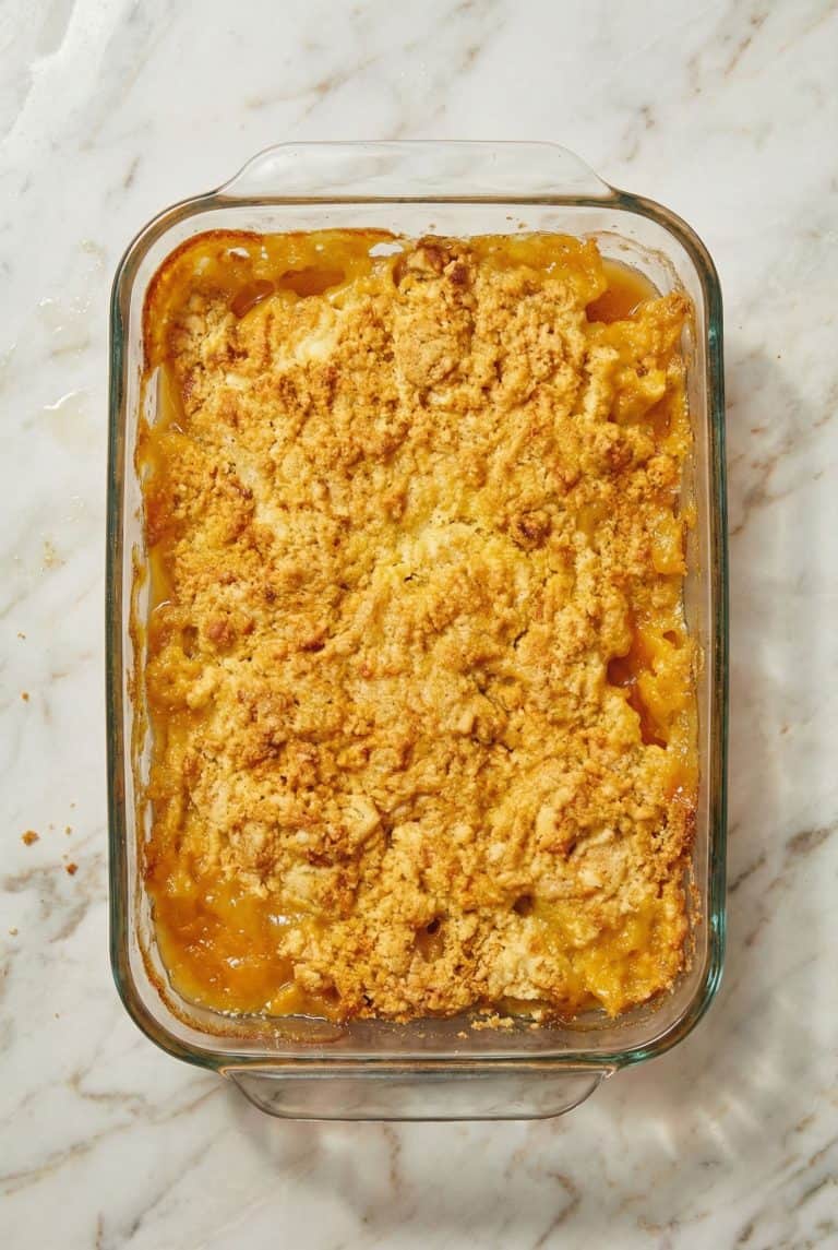 Freshly baked 3 Ingredient Cake Mix Peach Cobbler in a glass baking dish, featuring a golden, buttery topping over sweet canned peaches.
