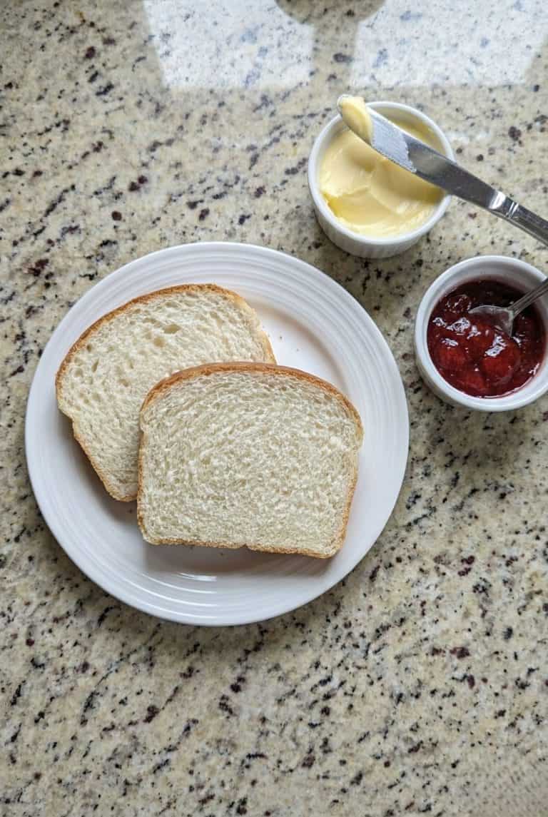 Two slices of homemade Amish white bread on a plate, an easy and delicious way to enjoy this soft, fluffy loaf from the recipe.