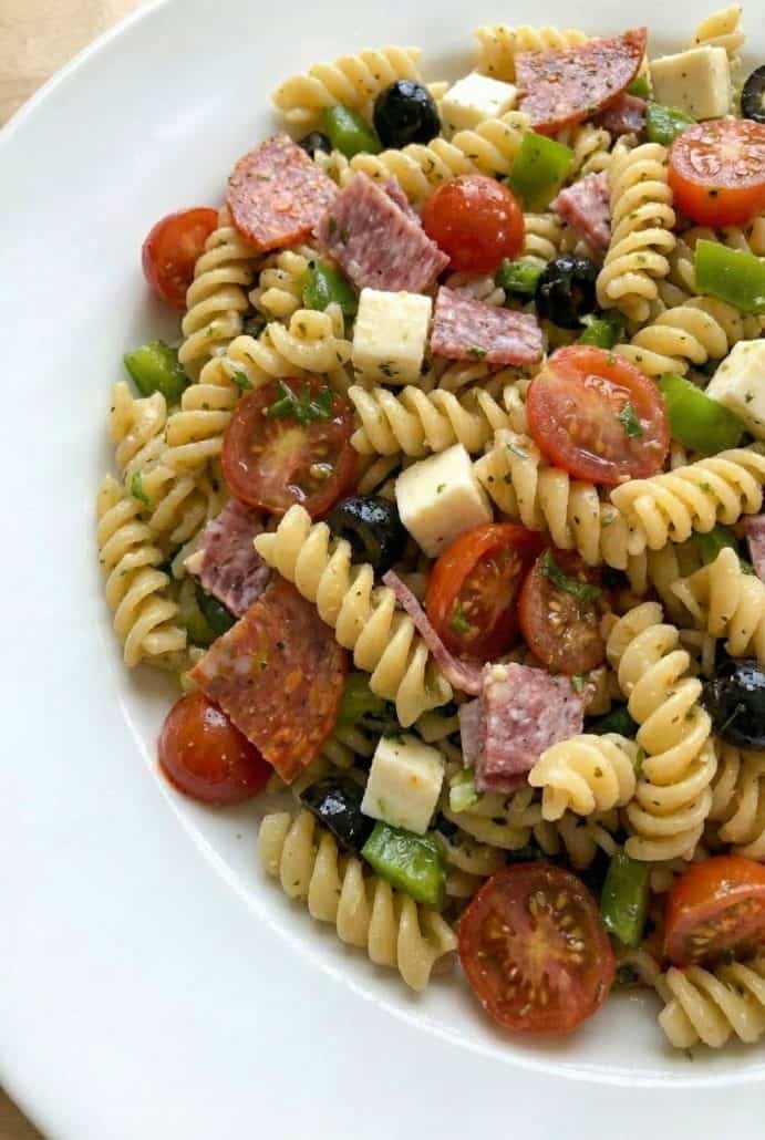 Close-up of Antipasto Pasta Salad highlighting rotini, cherry tomatoes, olives, salami, pepperoni, and cheese. Showing the vibrant, fresh ingredients in this easy cold pasta recipe.