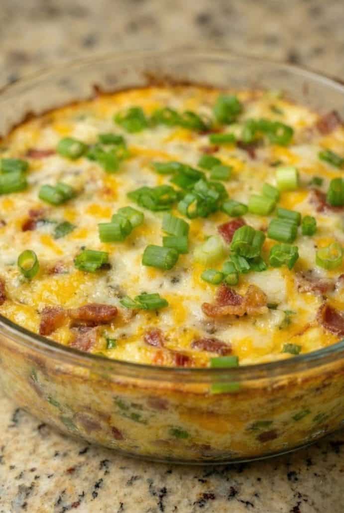 Close-up of hot Baked Buffalo Chicken Dip in a glass dish, loaded with melted cheese, bacon, and chopped green onions.