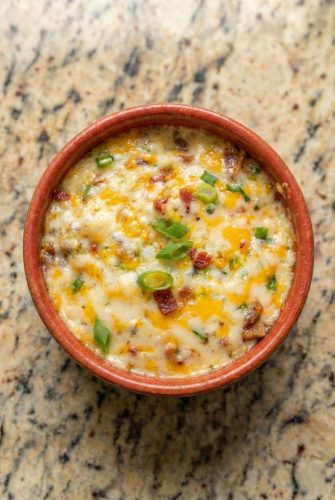 Baked Buffalo Chicken Dip Recipe - Easy Party Appetizer Baked Buffalo Chicken Dip served warm in a round dish, topped with melted cheese and green onions.