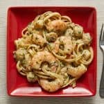 Plate of creamy Cajun seafood pasta with shrimp and scallops served on a red square dish.