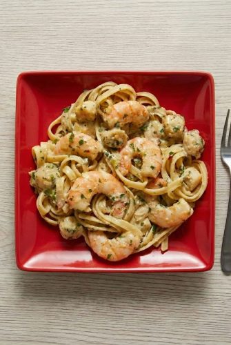 Plate of creamy Cajun seafood pasta with shrimp and scallops served on a red square dish.