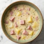 Bowl of creamy ham and potato soup with chunks of ham and tender potatoes, showing the finished dish.