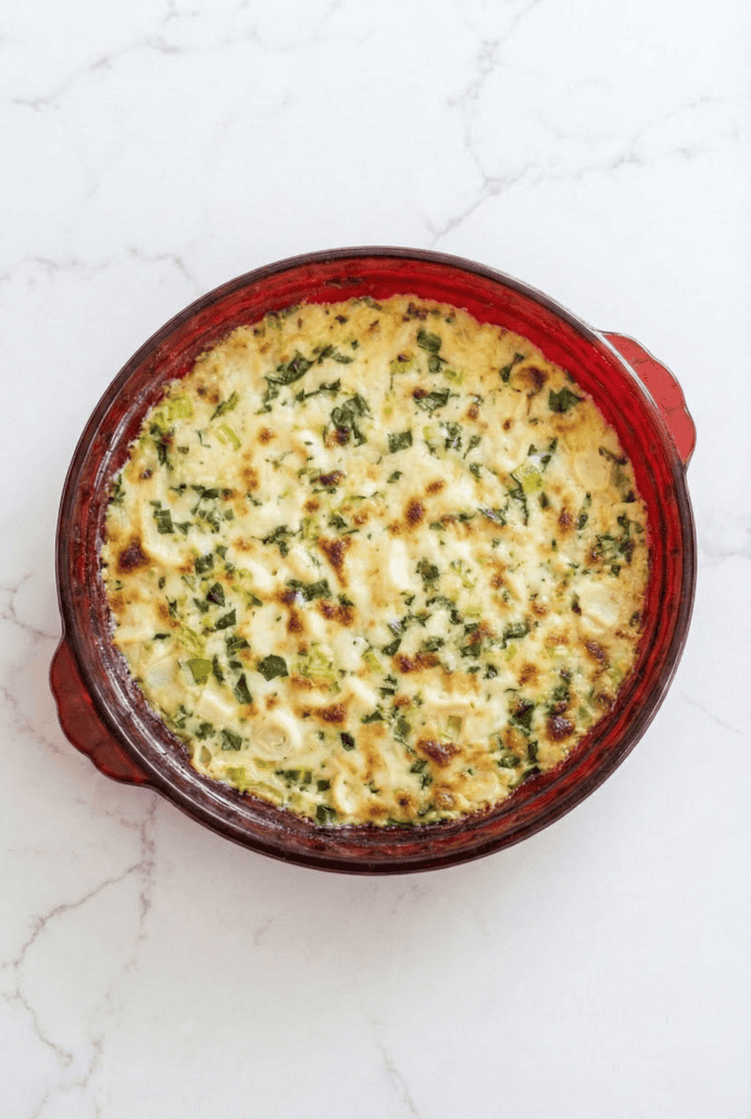Hot and bubbly hearts of palm dip baked in a red pie dish, ready to serve as a cheesy appetizer.