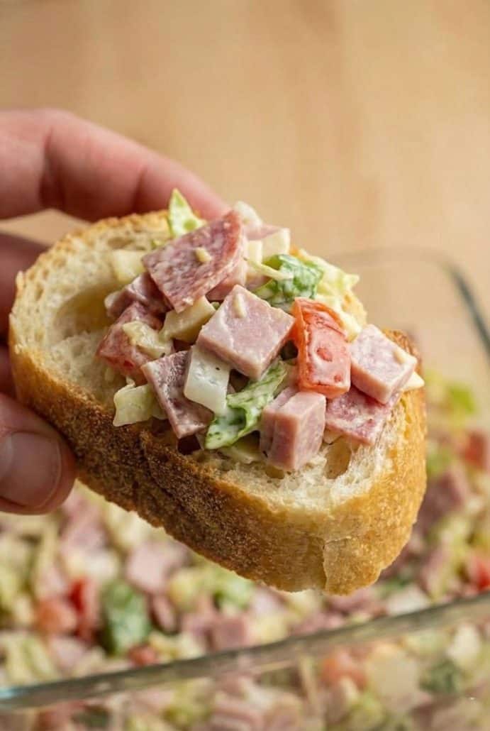 Close-up of hoagie dip scooped onto a slice of baguette. A flavorful, bite-sized appetizer perfect for parties.