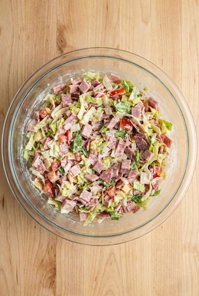 Glass bowl filled with chopped hoagie dip made from deli meats, lettuce, and tomatoes, ready to serve as a party appetizer.