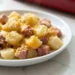 Plate of cheesy ham and potato casserole served hot, perfect for using up leftover holiday ham.