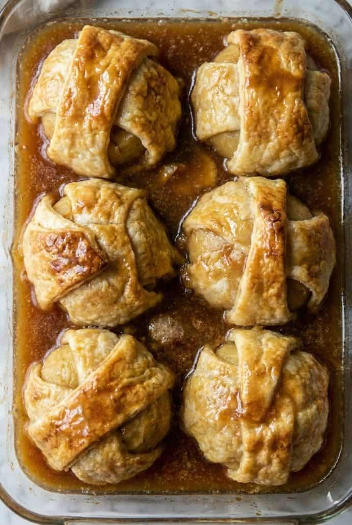 Golden brown old-fashioned apple dumplings baked in a vanilla sugar sauce, straight from the oven and ready to serve.