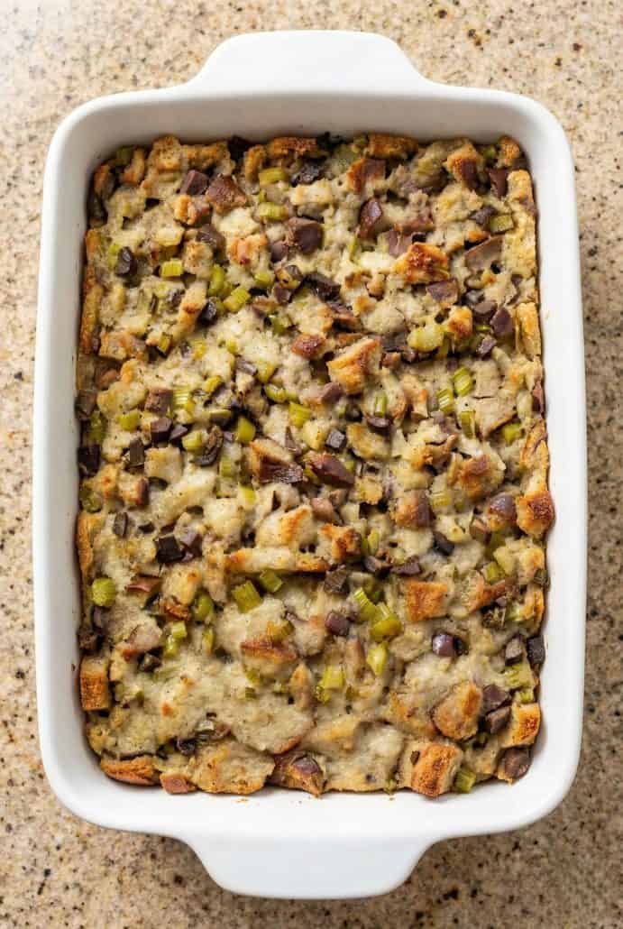 Baked old-fashioned giblet stuffing in a white casserole dish, showing golden brown bread cubes with turkey giblets, celery, and onions.