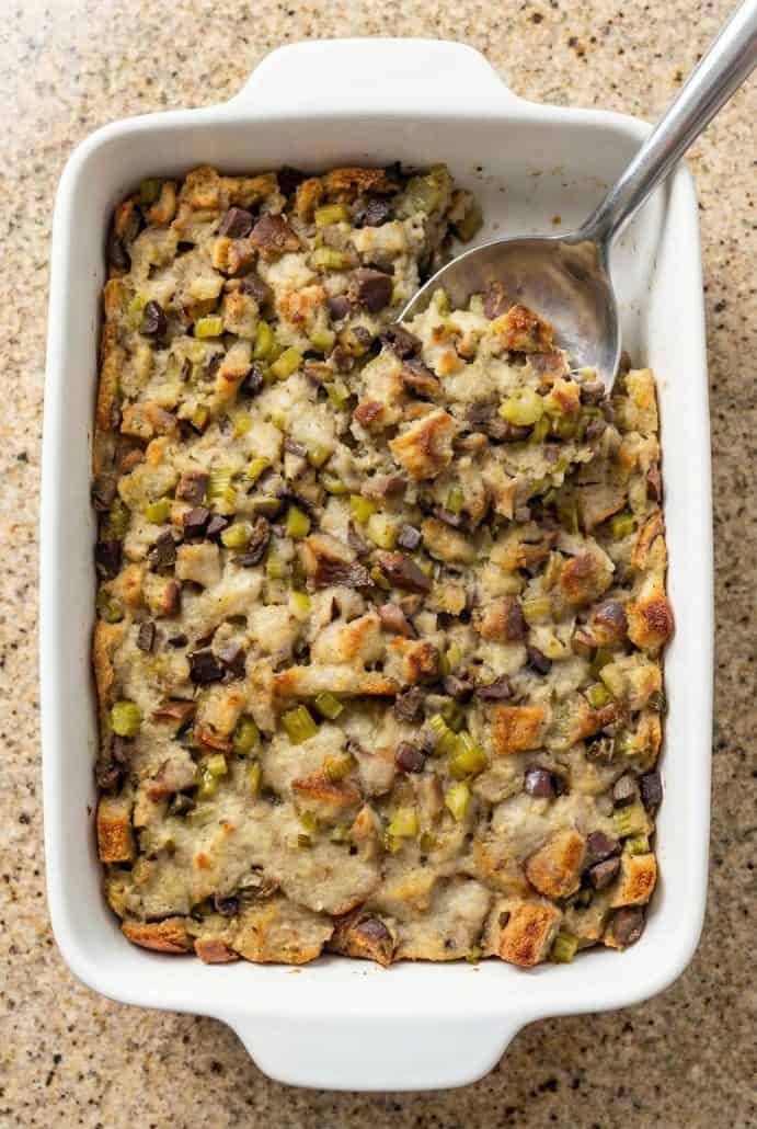 Casserole dish of baked giblet stuffing with a serving spoon, showing the moist and savory texture.