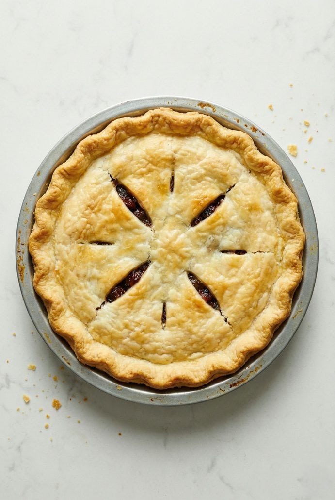 Whole baked old fashioned raisin pie with a golden, flaky crust and decorative slits.